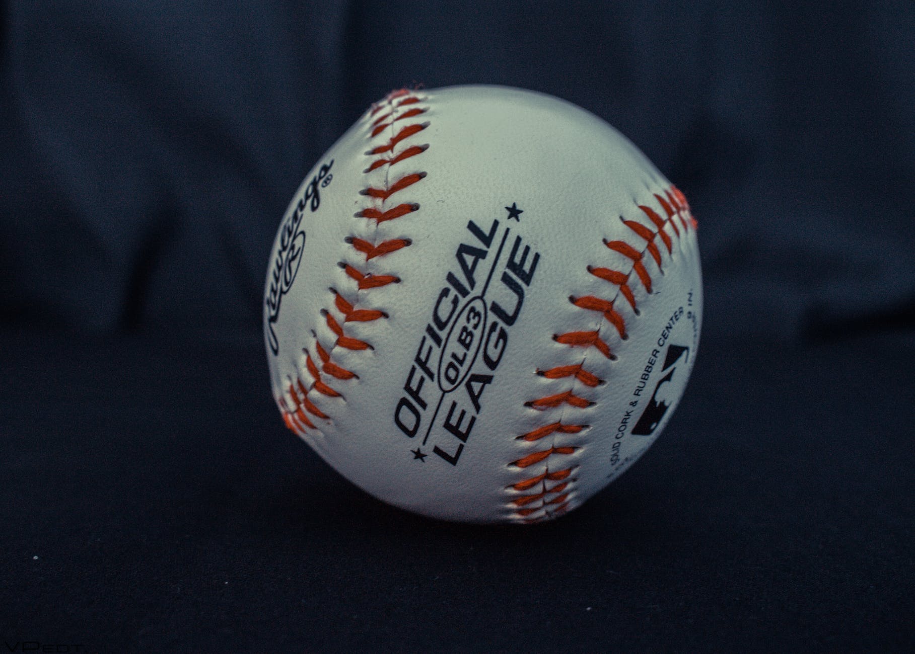 white and orange official league baseball on black textile