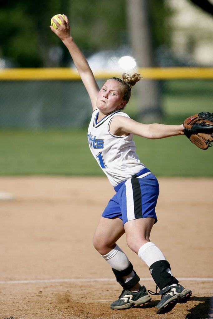 concentrated female baseball pitcher throwing baseball