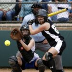 two female in baseball gears in stadium ready to catch and swing baseball