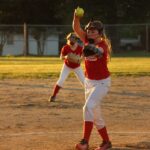 girl wearing baseball mitts holding soft ball